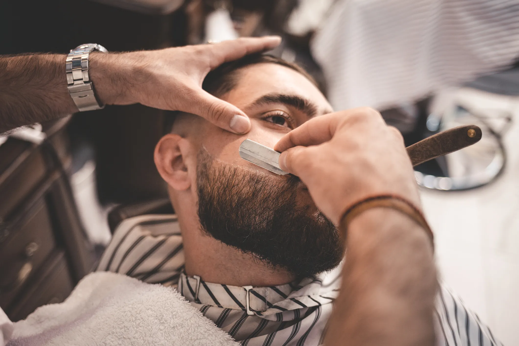 Barber giving a traditional straight razor shave at Taurus Barbershop